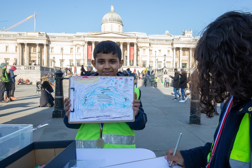A young artist shows his colourful sketch in Trafalgar Square