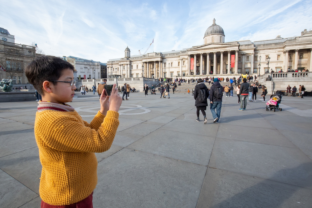 Schoolboy takes photograph in Trafalgar Square