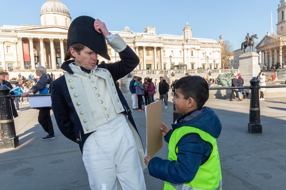 Pupil from Nelson School in Newham, London, showing his artwork to historic naval lieutenant